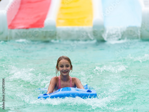 Little girl on water slide at aquapark. Summer holiday.