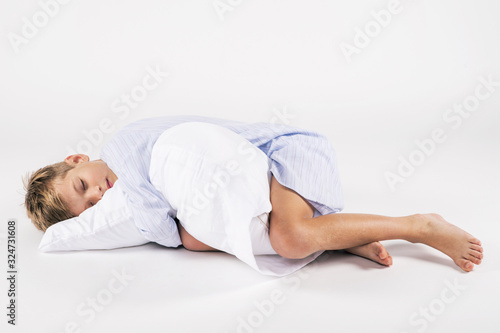 Sleeping boy in nightshirt cuddling with pillow