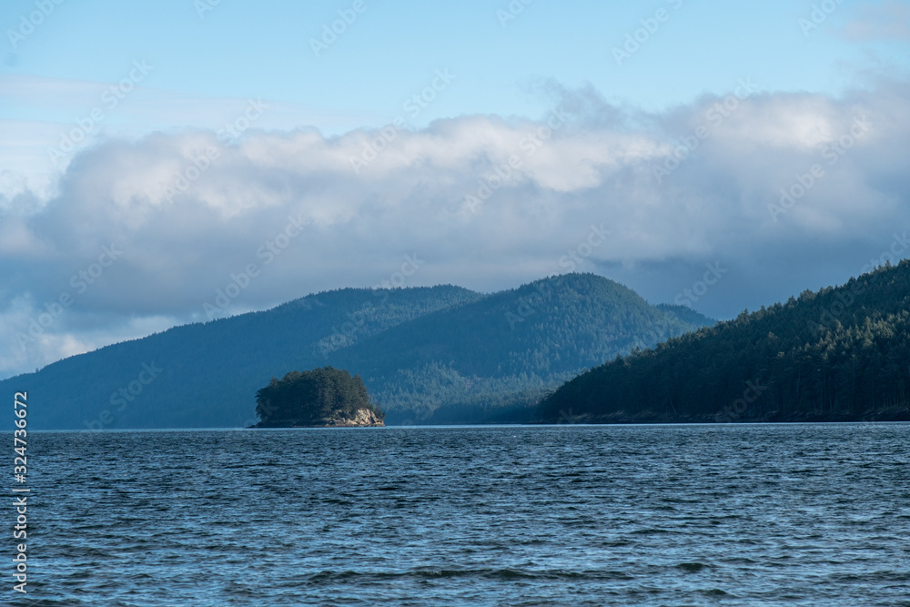 small island besides big ones on the blue ocean under cloud filled blue sky
