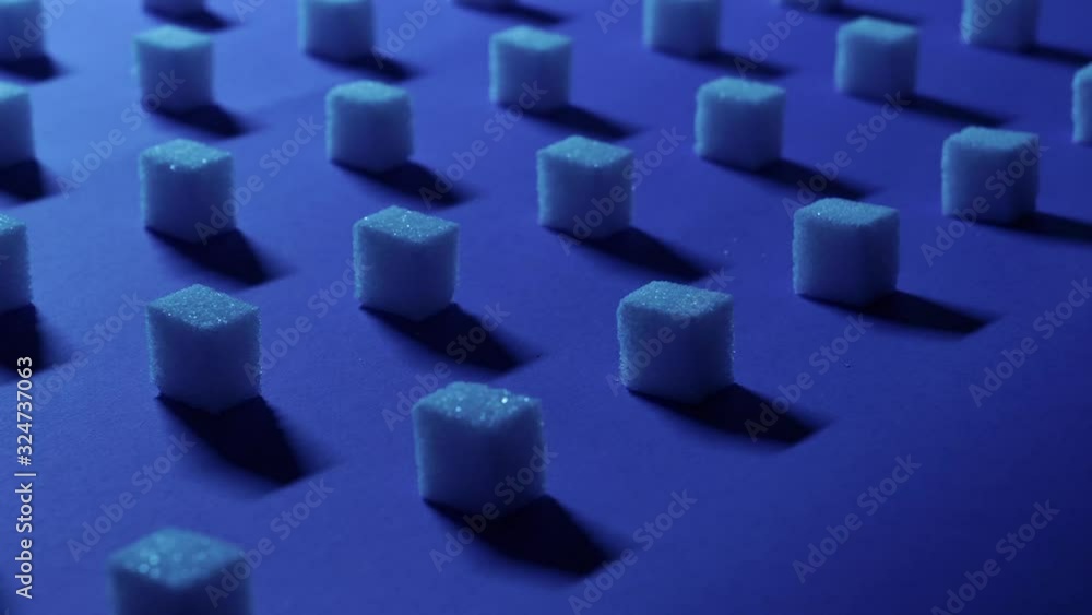 Slow low angle right to left panning view of a unique cubic background with white sugar cubes arranged in rows on a dark blue background, 3D effect. Slow low angle right to left panning view of a unique cubic background with white sugar cubes arranged in rows on a dark blue background, 3D effect.