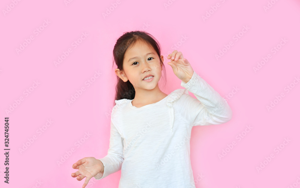 Portrait of smiling asian little child girl with expression finger holding something without theme isolated on pink background.