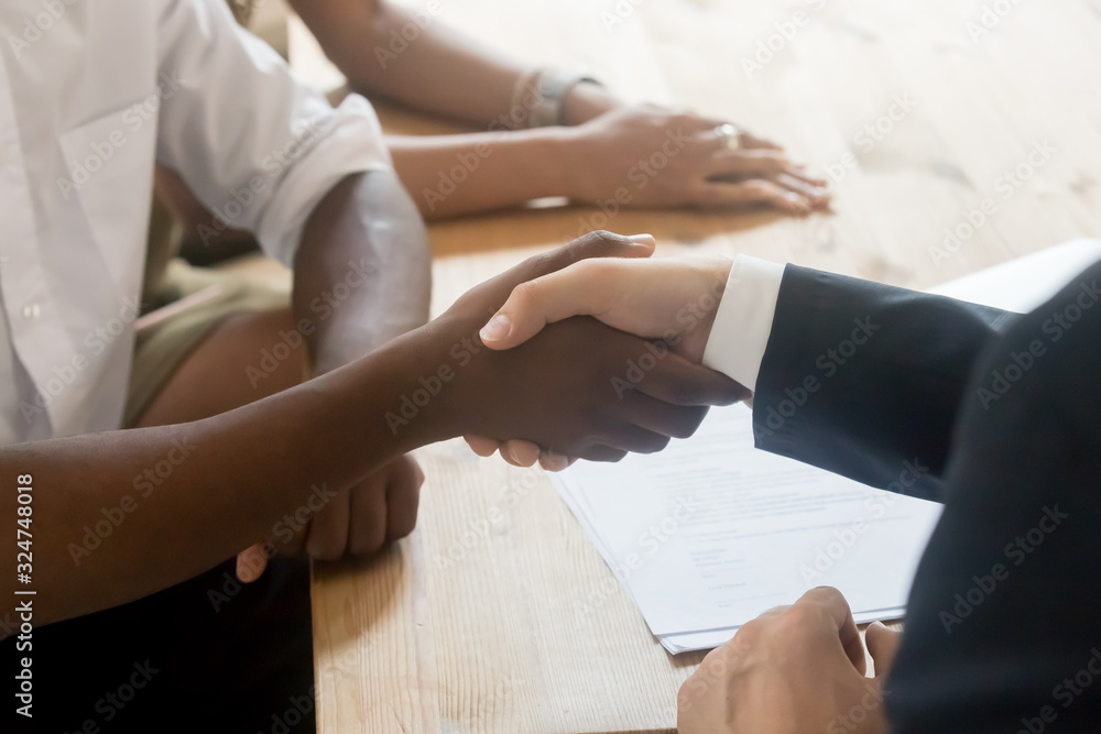 Close up African American client shaking hand of manager, agreement