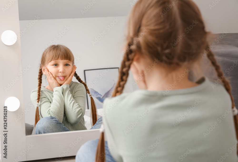 Funny little girl looking in mirror at home Funny little girl looking in mirror at home