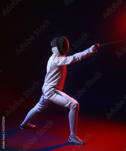 Toned photo of young fencer on dark background