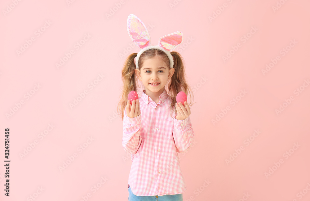 Little girl with Easter eggs and bunny ears on color background