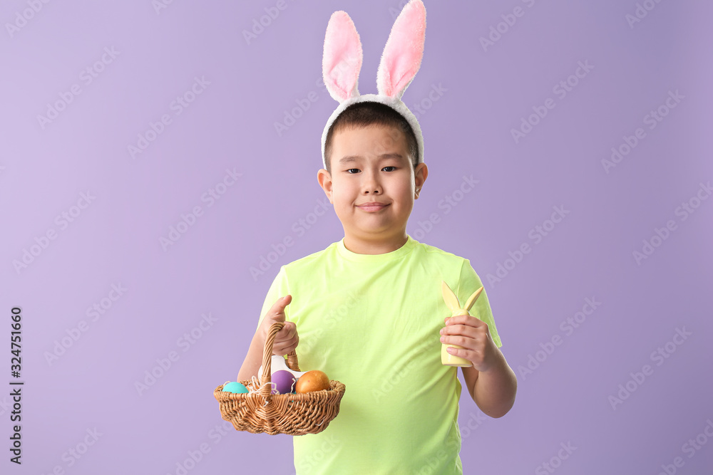 Little Asian boy with Easter eggs and bunny on color background Little Asian boy with Easter eggs and bunny on color background
