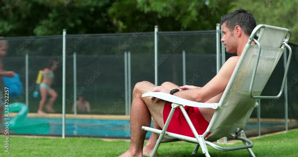 Kid In Pool With Parent Man observing kids play at the swimming pool. Parent guarding children ...