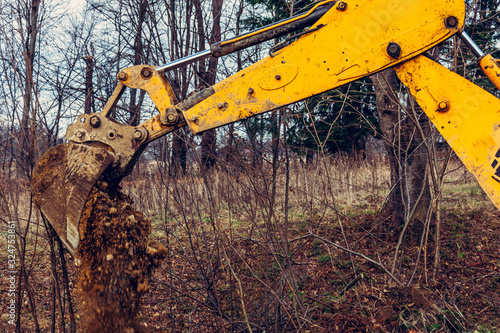 The excavator digs soil into the forest and uproots the roots of the trees. photo