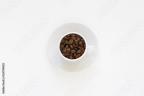 white cup with coffee beans on a white background, top view