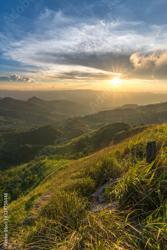 A beautiful scenery of sunset over Doi Pha Tang with a green grass field foreground in Chiang Rai, Thailand.