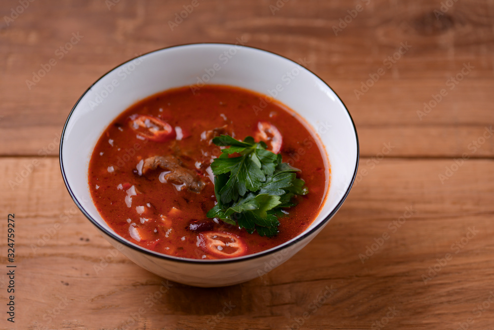 Traditional Ukrainian Russian vegetable borscht in a white bowl on the old rustic wooden background. Traditional Ukrainian Russian vegetable borscht in a white bowl on the old rustic wooden background.
