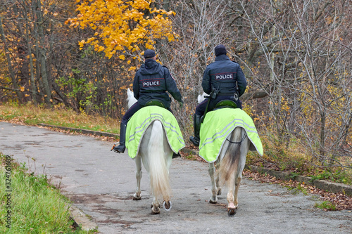 Mounted police in autumn city park, back view