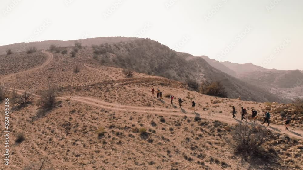 Local bedouin guide hikers while crossing hill top. Aerial drone shot from above Jordan, Dana Biosphere Reserve Local bedouin guide hikers while crossing hill top. Aerial drone shot from above Jordan, Dana Biosphere Reserve