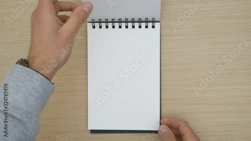 Man passing the sheets of a blank drawing pad. Blank spiral sketchpad.