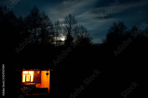 Photo The window glows at night on a gloomy moonlit sky.