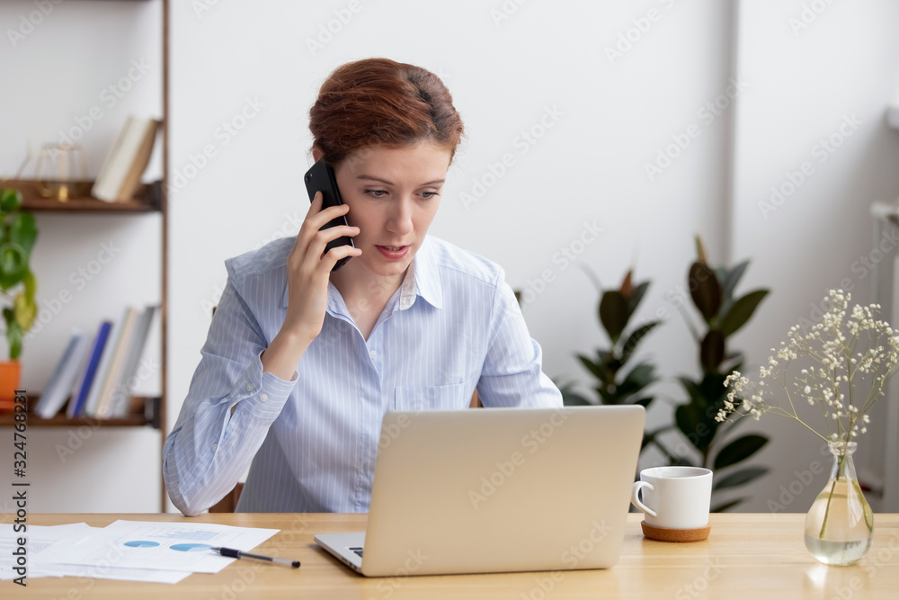 Busy businesswoman talking on phone, using laptop, consulting client Busy businesswoman talking on phone, using laptop, consulting client