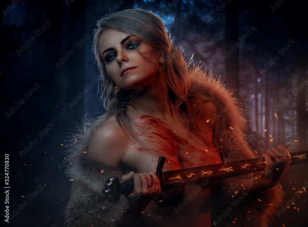 Fototapeta Beautiful naked woman with blood stained skin holding a long sword in night forest. Fantasy fashion. Cosplayer as Ciri from The Witcher