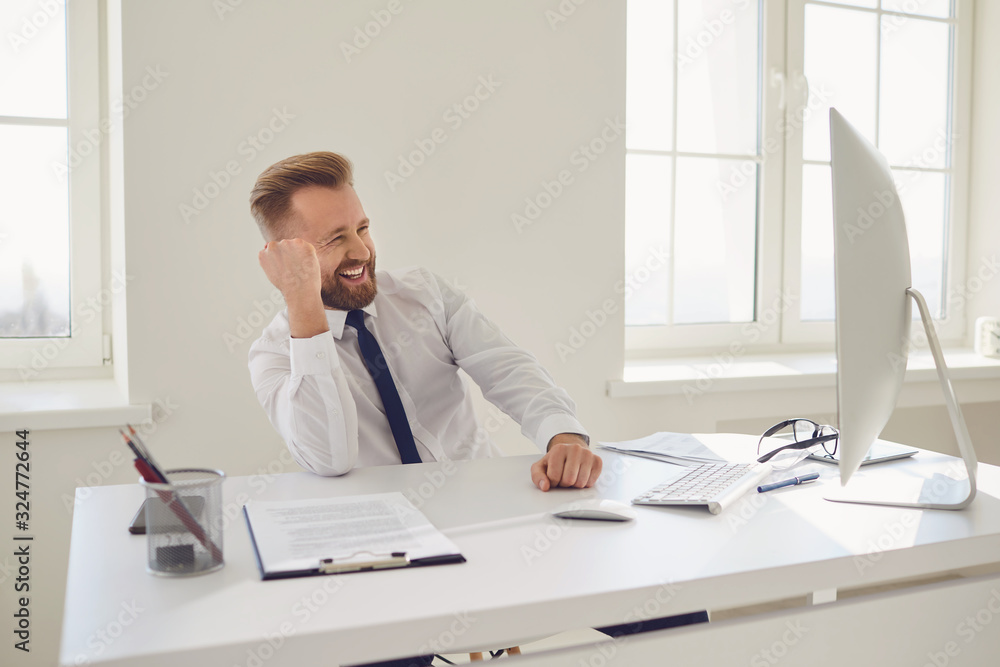 Happy blonde businessman raised his hand up working in office