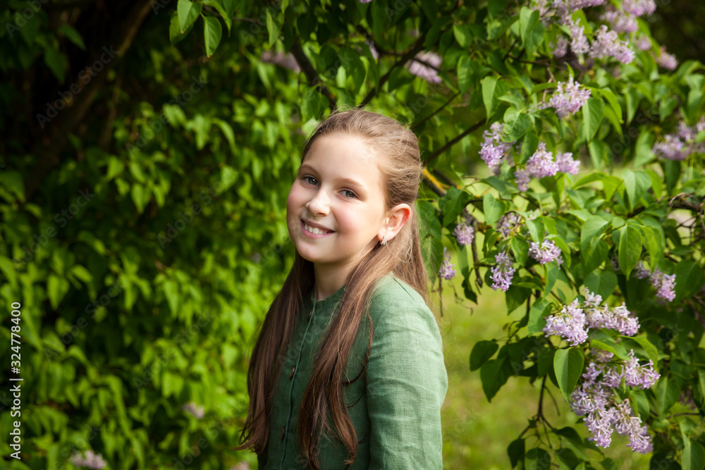 Cute girl has fun in the park with blooming lilacs, enjoys spring and warmth Cute girl has fun in the park with blooming lilacs, enjoys spring and warmth