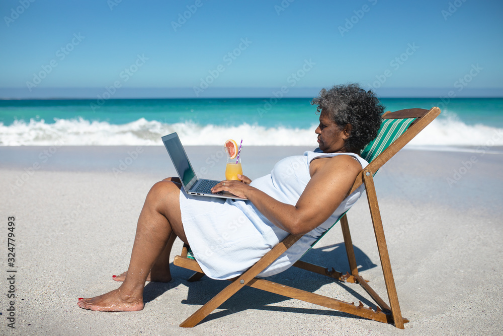 Old woman on laptop at the beach