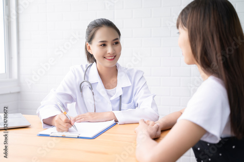 Asian female Doctor and patient are discussing something ,Having Consultation,Medical physician working in hospital writing a prescription, Healthcare and medically concept,selective focus