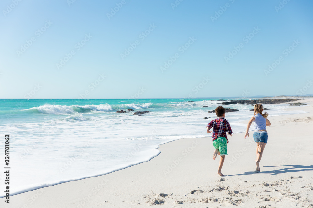 Brother and sister running at the beach Brother and sister running at the beach