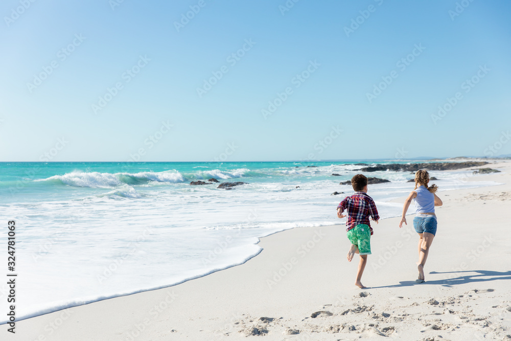 Brother and sister running at the beach