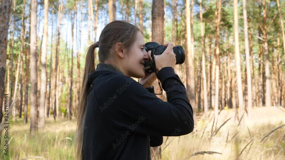 4k video of young female wildlife photographer making images of nature while standing in high grass at forest 4k video of young female wildlife photographer making images of nature while standing in high grass at forest