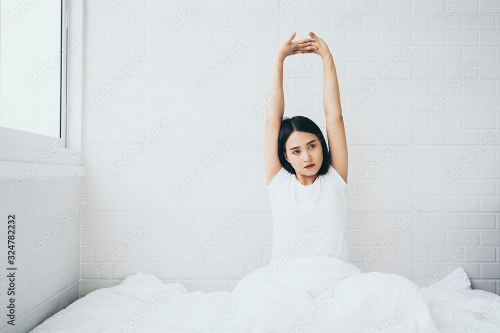 Beautiful Asian woman waking up on her bed in the bedroom, she is stretching and smiling after wake up, Asia women exercising in the morning, feels refreshed.good dream last night, lifestyle in home - obrazy, fototapety, plakaty 