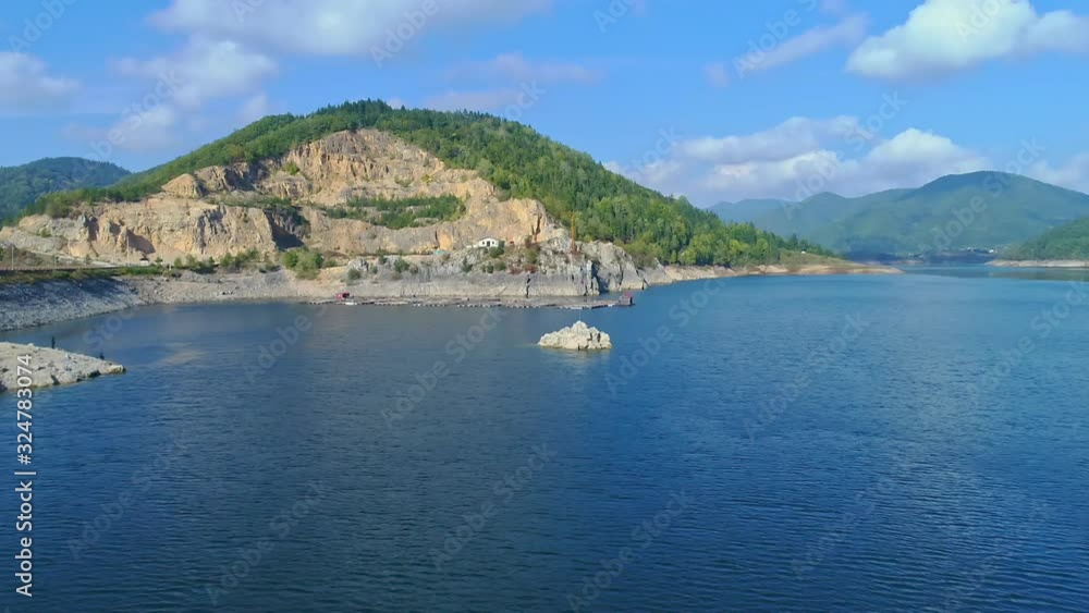 Aerial flying over a Serbian flag waving on a rock over Zaovine lake. Dolly in Aerial flying over a Serbian flag waving on a rock over Zaovine lake. Dolly in