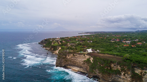 Aerial view of sea rocky coast with surf the waves, Bali, Indonesia, Pura Uluwatu cliff. Waves crushing rocky shore. Seascape, rocks, ocean. Travel concept.