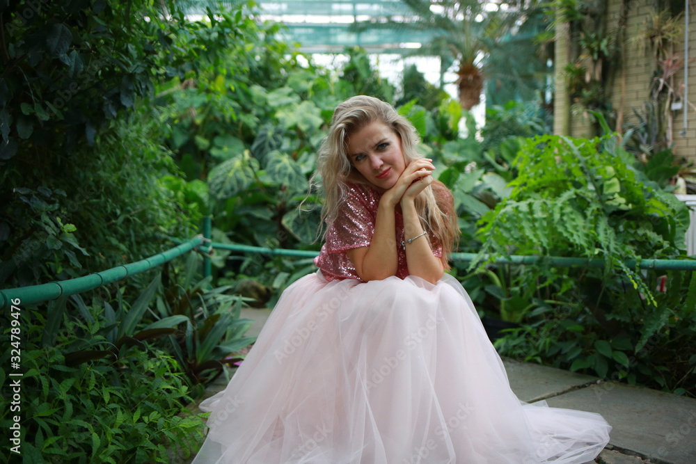 beautiful white long hair girl in a tropical garden in a light tulle pink skirt beautiful white long hair girl in a tropical garden in a light tulle pink skirt
