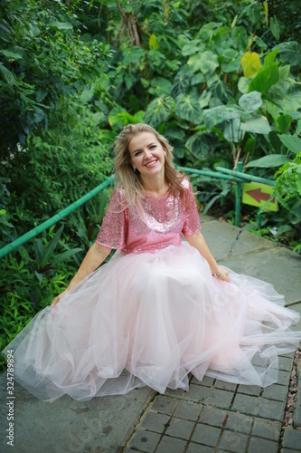  beautiful white long hair girl in a tropical garden in a light tulle pink skirt