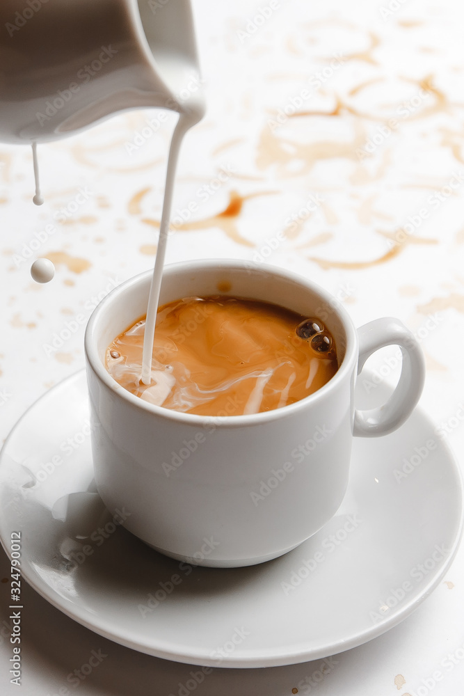 cream is poured into black coffee on a white background filled with coffee. a place for a label cream is poured into black coffee on a white background filled with coffee. a place for a label