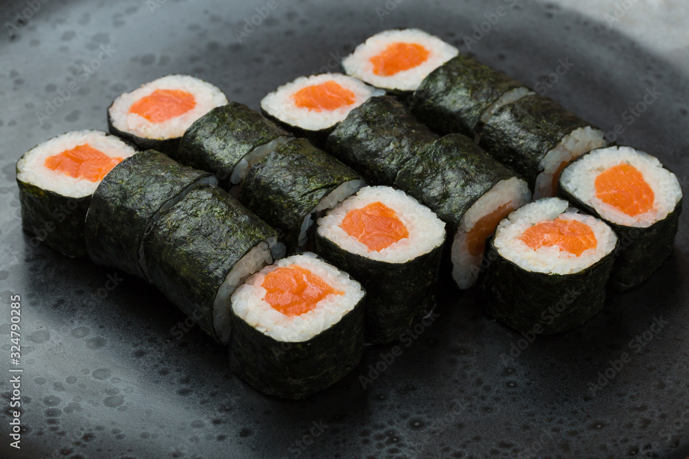 Hosomaki rolls closeup on a black plate with selective focus. Rolls with seaweed, rice, salmon Hosomaki rolls closeup on a black plate with selective focus. Rolls with seaweed, rice, salmon