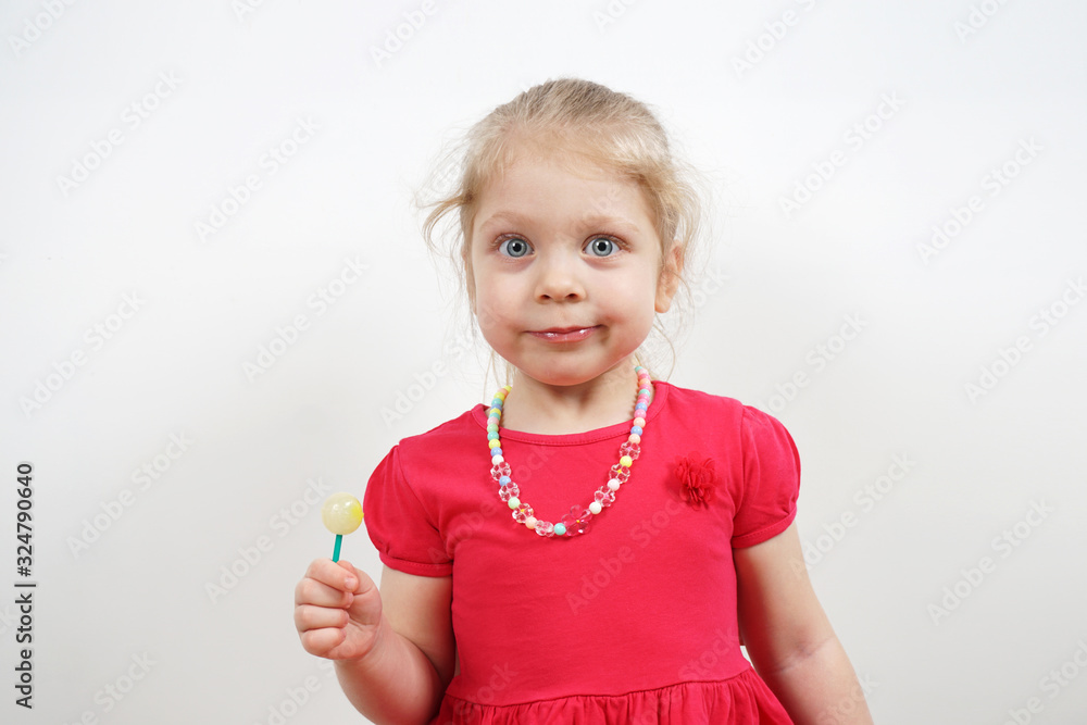 Cheerful little blonde girl in a pink dress for advertising. Lollipop in the hands. Cheerful little blonde girl in a pink dress for advertising. Lollipop in the hands.