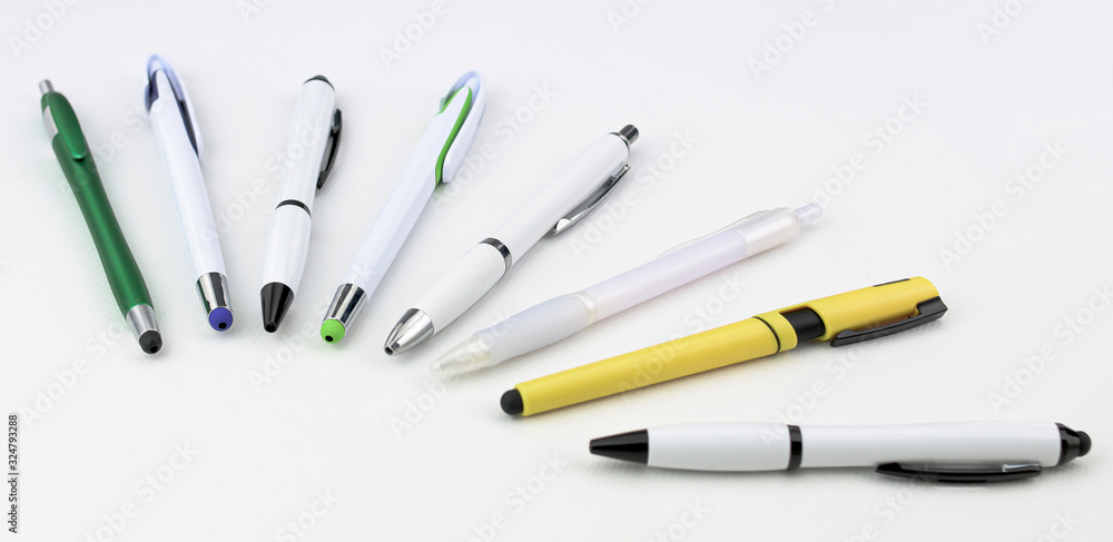 Aligned pens of different styles and colors on white background