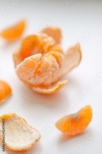 ripe mandarin with slices and peel on a white table.