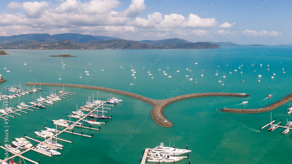 Panoramic marina town aerial. Airlie beach waterfront aerial view. Dramatic DRONE view from above. Marina town with yachts and boats in sea water. Mountain landscape background. Whitsundays Islands Panoramic marina town aerial. Airlie beach waterfront aerial view. Dramatic DRONE view from above. Marina town with yachts and boats in sea water. Mountain landscape background. Whitsundays Islands