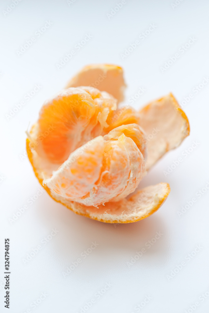 ripe orange mandarin with opened peel on a white table. ripe orange mandarin with opened peel on a white table.