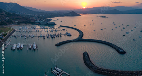 Sunset Panoramic marina town aerial. Airlie beach waterfront aerial view. Dramatic DRONE view from above. Marina town with yachts and boats in sea water. Mountain landscape. Whitsundays Islands