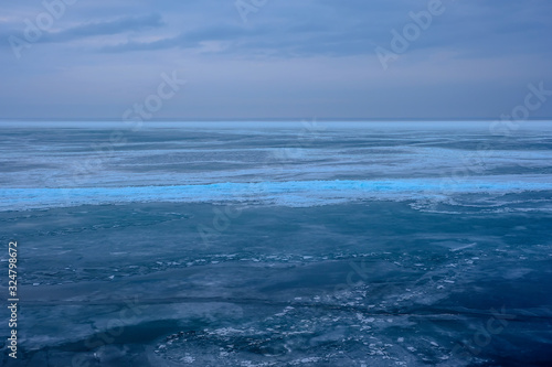 Field of ice hummocks on the frozen lake. Cracked ice on lake in winter season, natural landscape background. © Adil