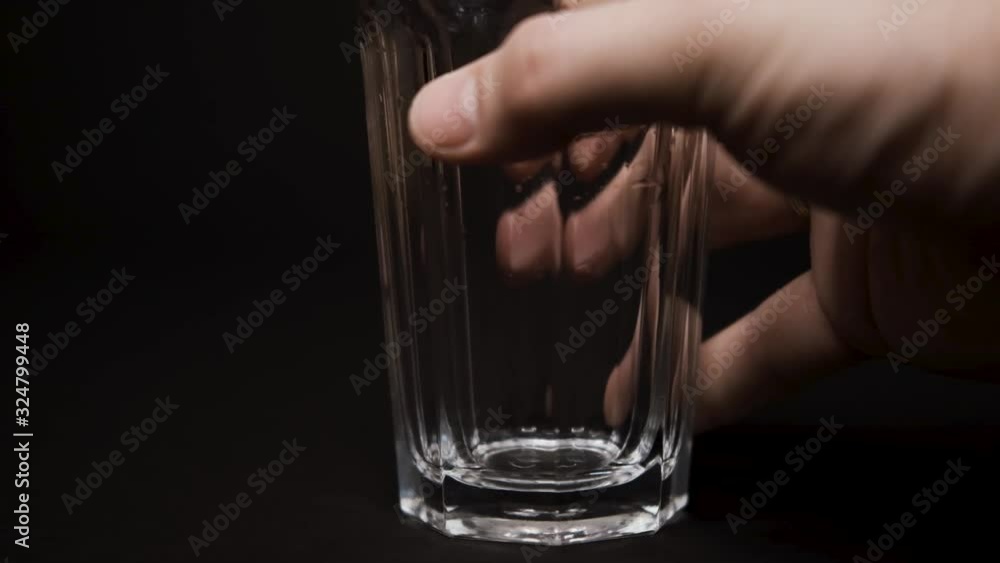male hand takes a glass of water on a black background, a trace on the table from the water caucasian slow mo male hand takes a glass of water on a black background, a trace on the table from the water caucasian slow mo