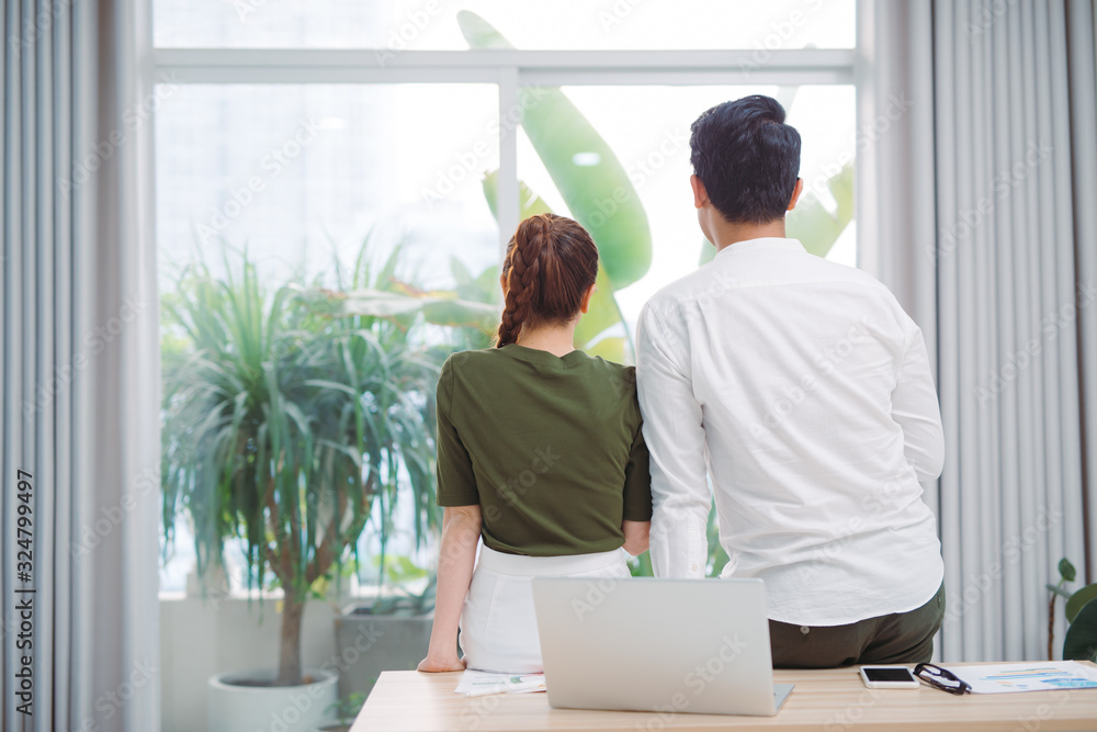 Cute couple looking out the window after work
