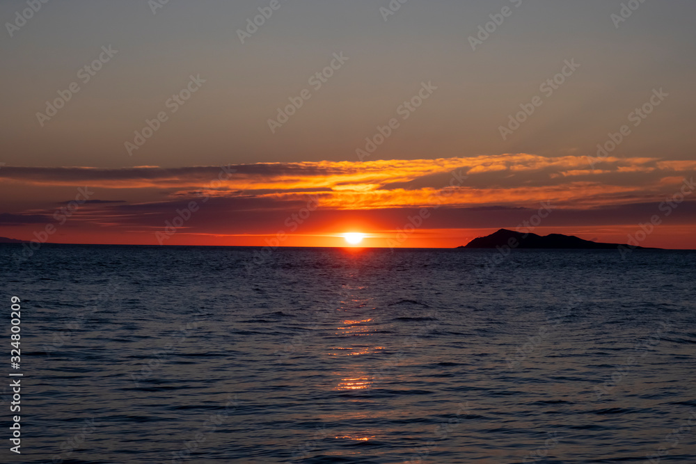 Fototapeta premium Beautiful sea sunset with island silhouette. Orange sunrise over the sea.