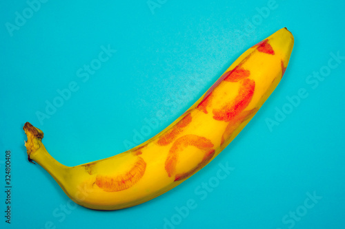 Red lipstick on a yellow banana on a blue background. Oral sex concept.