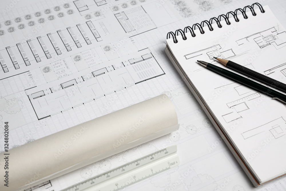 Architect scale ruler, pencil, mechanical pencil, notebook and building blueprint on worktable Architect scale ruler, pencil, mechanical pencil, notebook and building blueprint on worktable
