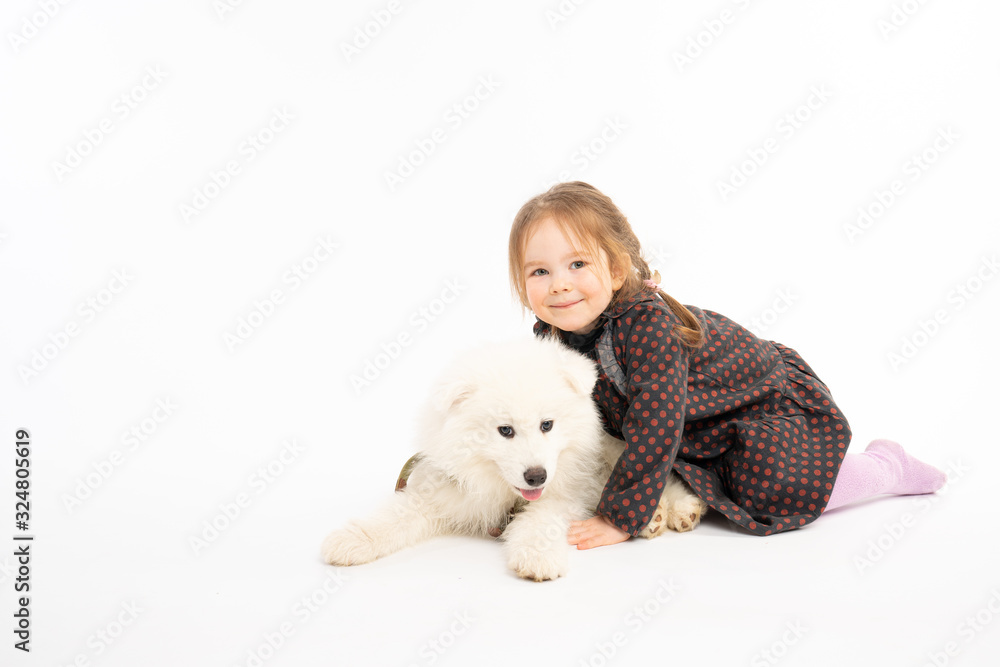 Pretty cute photo of beautiful redhead girl in dress and white samoyed puppy that liying on the floor and looking at the camera isolated over white background