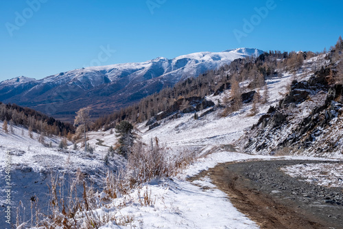 Mountains landscape with dangerous gravel road. First snow in the mountains.