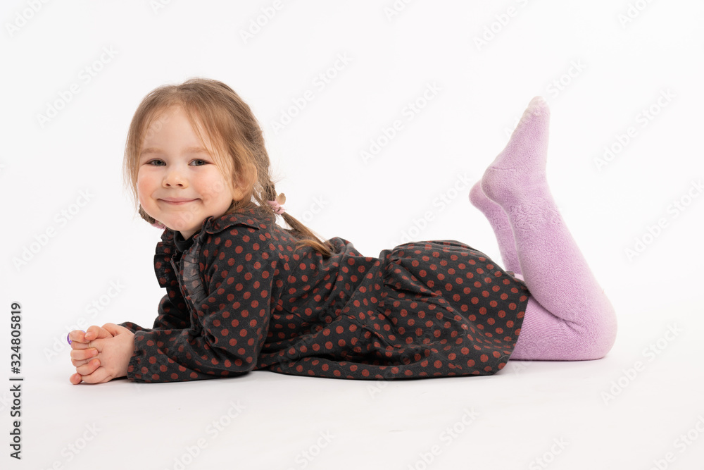 Happy adorable redhead little girl in dress smiling and looking at the camera while liying on the ground Happy adorable redhead little girl in dress smiling and looking at the camera while liying on the ground